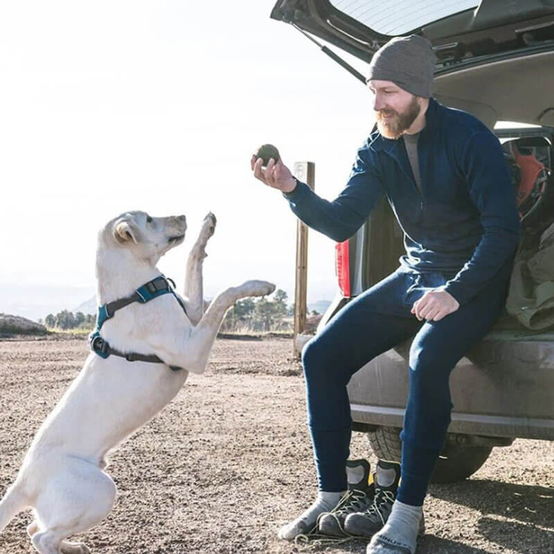 Man in merino wool thermal underwear with dog outdoors, showcasing cold-weather gear in action. Perfect for winter adventures.